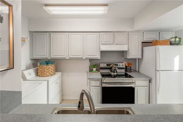 a kitchen with stainless steel appliances granite countertop a stove a refrigerator and a white cabinets