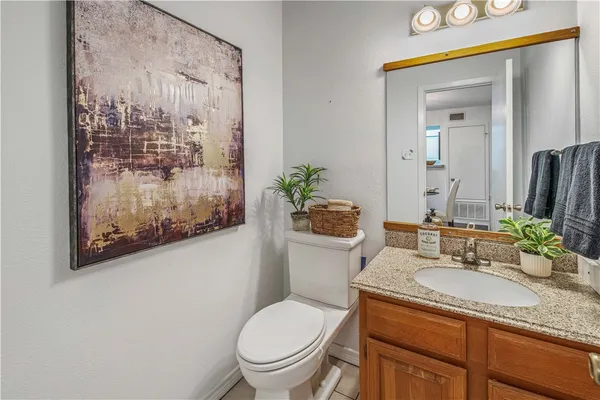 a bathroom with a granite countertop toilet a sink and mirror