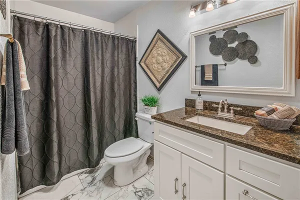 a bathroom with a granite countertop sink a toilet and a mirror
