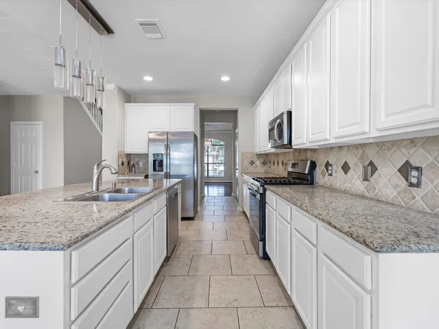 a kitchen with stainless steel appliances granite countertop a sink stove and cabinets