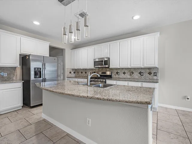 a kitchen with stainless steel appliances granite countertop a sink refrigerator and microwave