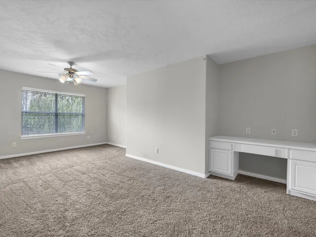 an empty room with chandelier fan and windows