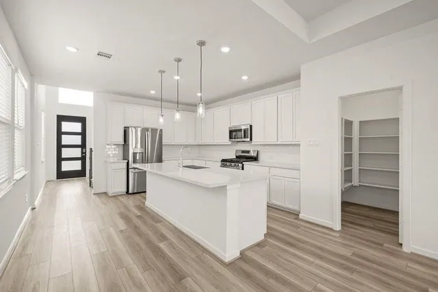 a kitchen with stainless steel appliances kitchen island granite countertop a stove a sink and a refrigerator