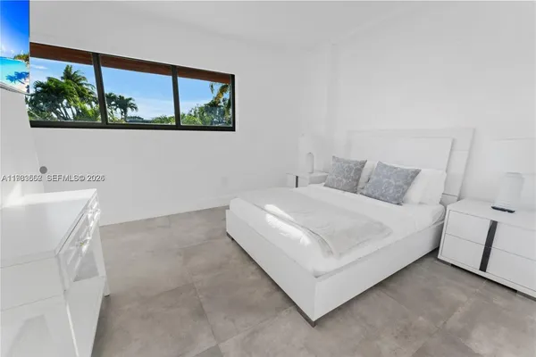 a white bed sitting in a bedroom next to a window