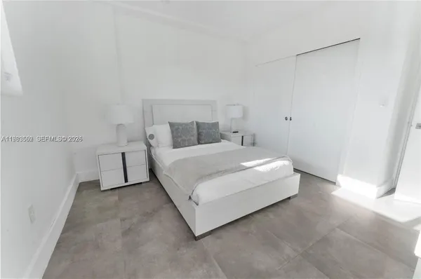 a white bed sitting in a bedroom next to a window
