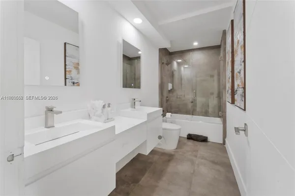 a bathroom with a bathtub shower sink mirror and toilet