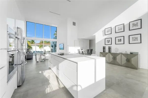 a living room with stainless steel appliances furniture a rug and a kitchen view