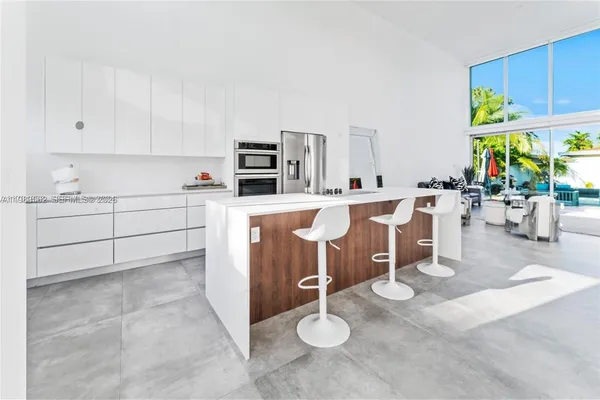 a room with stainless steel appliances kitchen island granite countertop a sink and cabinets