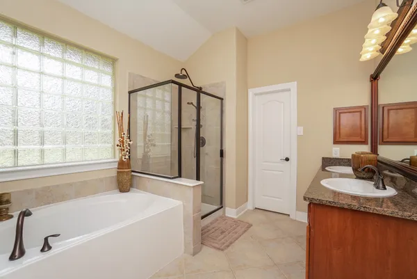 a bathroom with a granite countertop tub sink and mirror