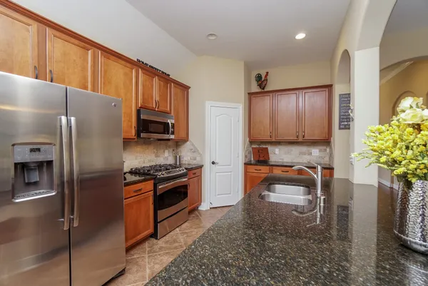 a kitchen with stainless steel appliances granite countertop a refrigerator a stove top oven a sink and dishwasher