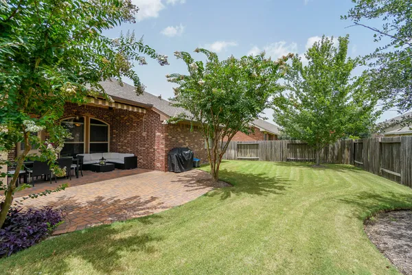 a backyard of a house with table and chairs under an umbrella
