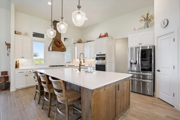a dining room with stainless steel appliances kitchen island granite countertop a table chairs and a refrigerator