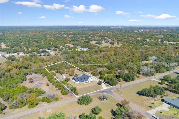 an aerial view of a house with a yard and trees all around