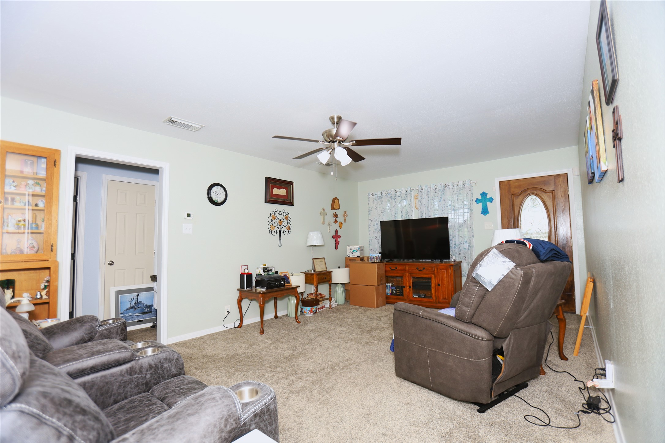 726 West 8th Street Freeport, TX 77541 - Photo 2 of 18 Living Room – Spacious living area with plush carpet, neutral tones, and a ceiling fan for comfort.
