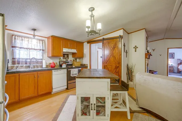 a kitchen with stainless steel appliances granite countertop a stove a sink dishwasher and a refrigerator with wooden floor