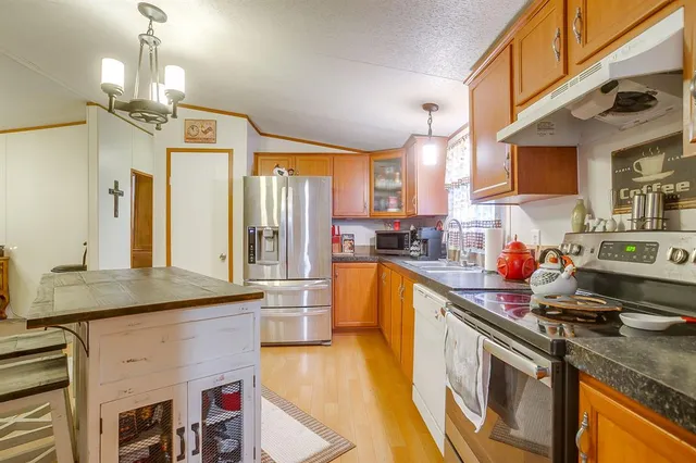 a kitchen with stainless steel appliances granite countertop a sink a stove and a wooden floors
