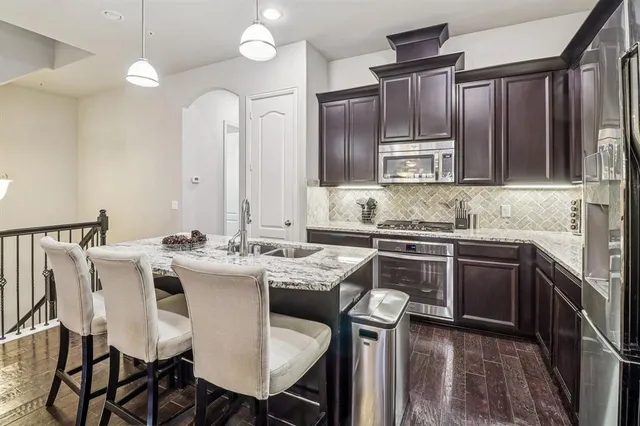 a kitchen with granite countertop a sink stainless steel appliances and cabinets
