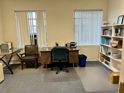 a view of a workspace with furniture and a window