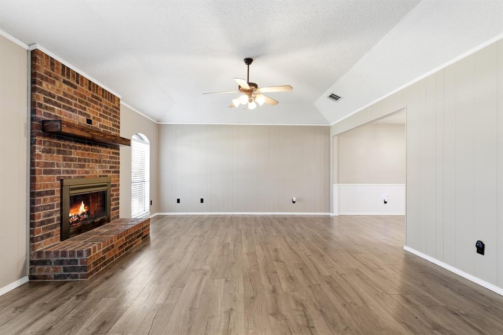 6612 Patsy Lane Watauga, TX 76148 - Photo 5 of 32 Spacious room featuring wood-finish flooring, a brick fireplace with a wood mantle, vaulted ceilings, and a ceiling fan