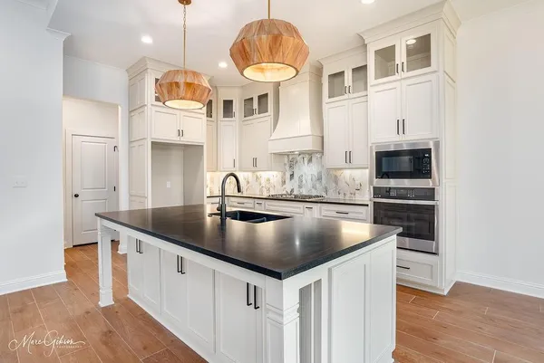 a large kitchen with stainless steel appliances kitchen island granite countertop a large cabinets a sink and a stove