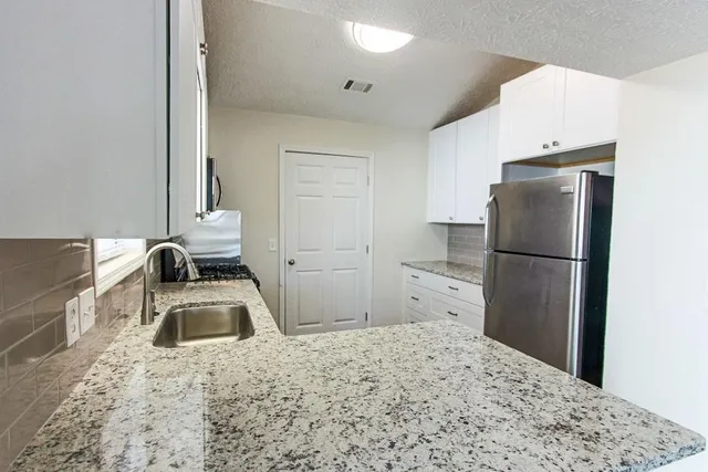 a bathroom with a granite countertop sink and a refrigerator