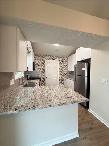 a view of a kitchen with white cabinets and wooden floor