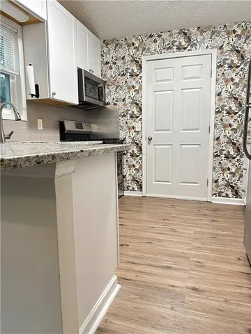 a kitchen with stainless steel appliances granite countertop a sink window and cabinets
