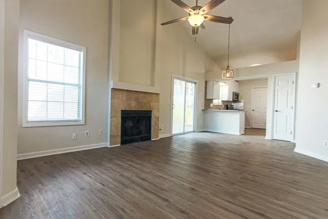 an empty room with wooden floor fireplace cabinet and windows