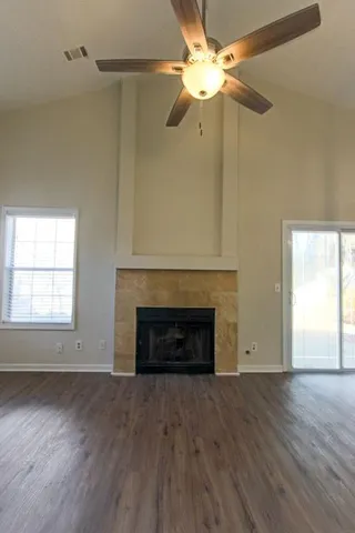an empty room with wooden floor a fireplace and windows