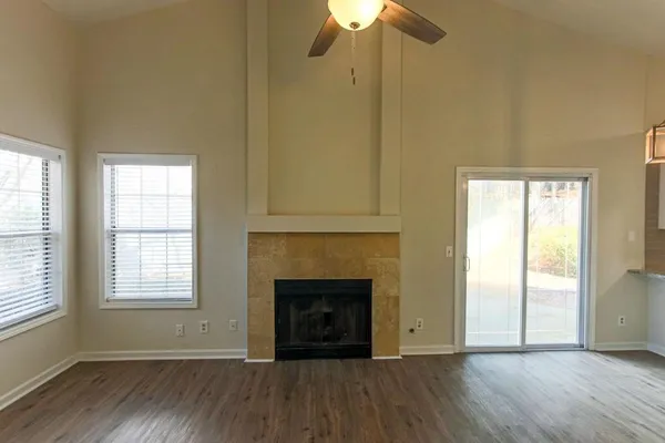 an empty room with wooden floor ceiling fan and windows