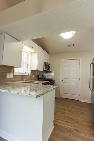 a kitchen with granite countertop white cabinets and refrigerator
