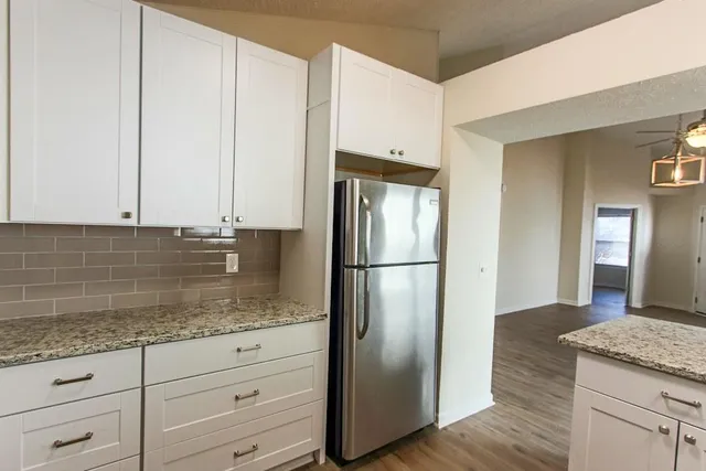 a kitchen with granite countertop a refrigerator and cabinets