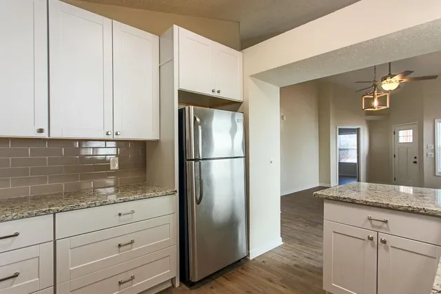 a kitchen with granite countertop a refrigerator and cabinets