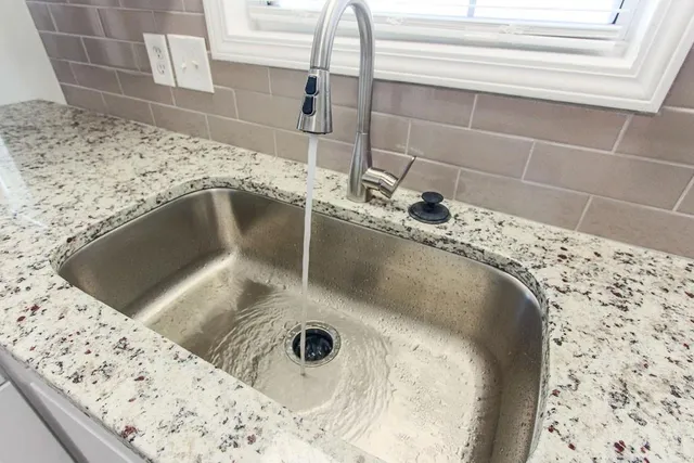 a kitchen with granite countertop white cabinets and stainless steel appliances