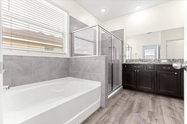 a bathroom with a tub sink shower and two mirror