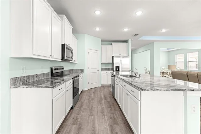 a kitchen with stainless steel appliances granite countertop a refrigerator sink and white cabinets