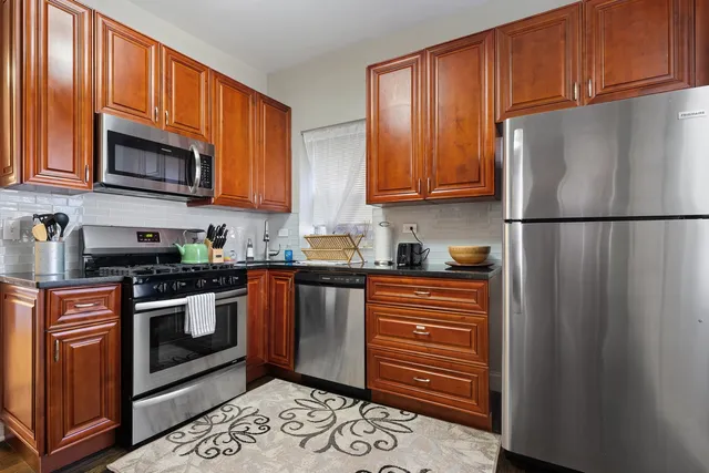 a kitchen with stainless steel appliances granite countertop a refrigerator stove a sink and dishwasher a oven with wooden cabinets