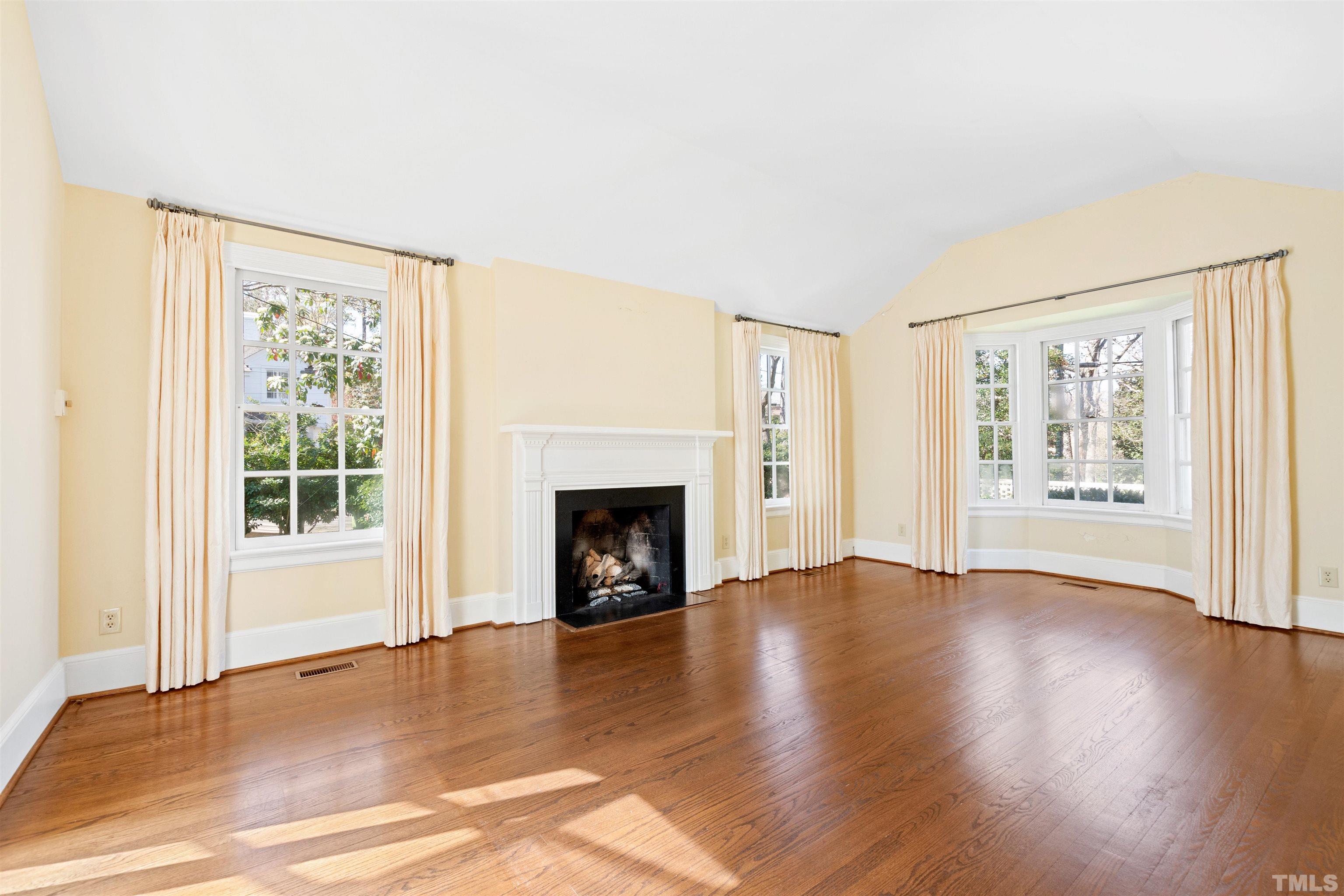 1718 Canterbury Road Raleigh, NC 27608 - Photo 10 of 30 an empty room with wooden floor fireplace and windows