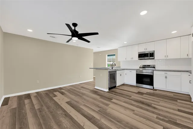 a view of an empty room with window and wooden floor