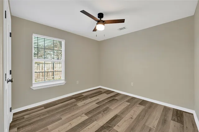 an empty room with a ceiling fan and wooden floor