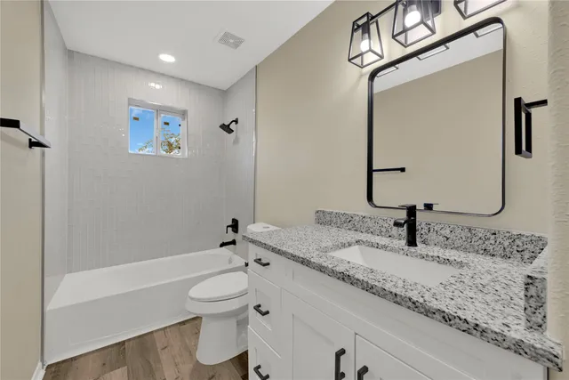 a bathroom with a granite countertop sink a toilet and a bathtub