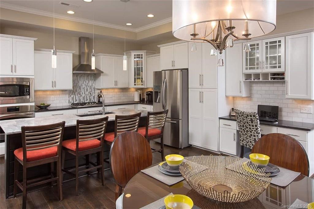 2018 New Style Way, Unit 5 Tega Cay, SC 29708 - Photo 12 of 36 a kitchen with stainless steel appliances granite countertop a stove a refrigerator a kitchen island a dining table and chairs with wooden floor