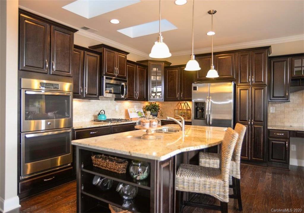 2018 New Style Way, Unit 5 Tega Cay, SC 29708 - Photo 23 of 36 a kitchen with stainless steel appliances granite countertop a stove a refrigerator a sink a dining table and chairs