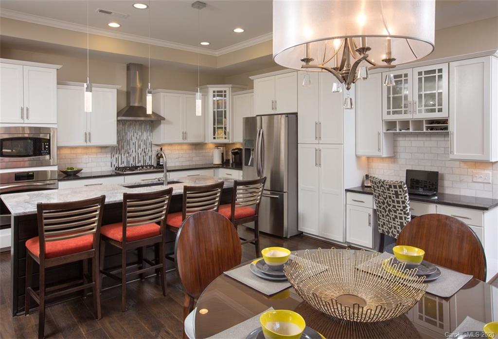 2018 New Style Way, Unit 5 Tega Cay, SC 29708 - Photo 4 of 36 a kitchen with stainless steel appliances granite countertop a sink a stove a dining table and chairs