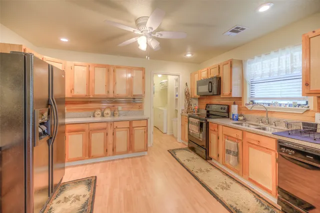 a large kitchen with stainless steel appliances granite countertop a refrigerator a sink dishwasher a stove and white countertops with wooden floor