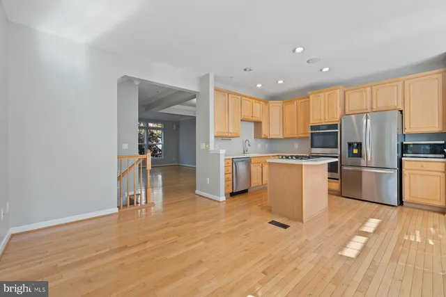 a open kitchen with granite countertop a stove top oven a sink dishwasher a dining table and chairs with wooden floor