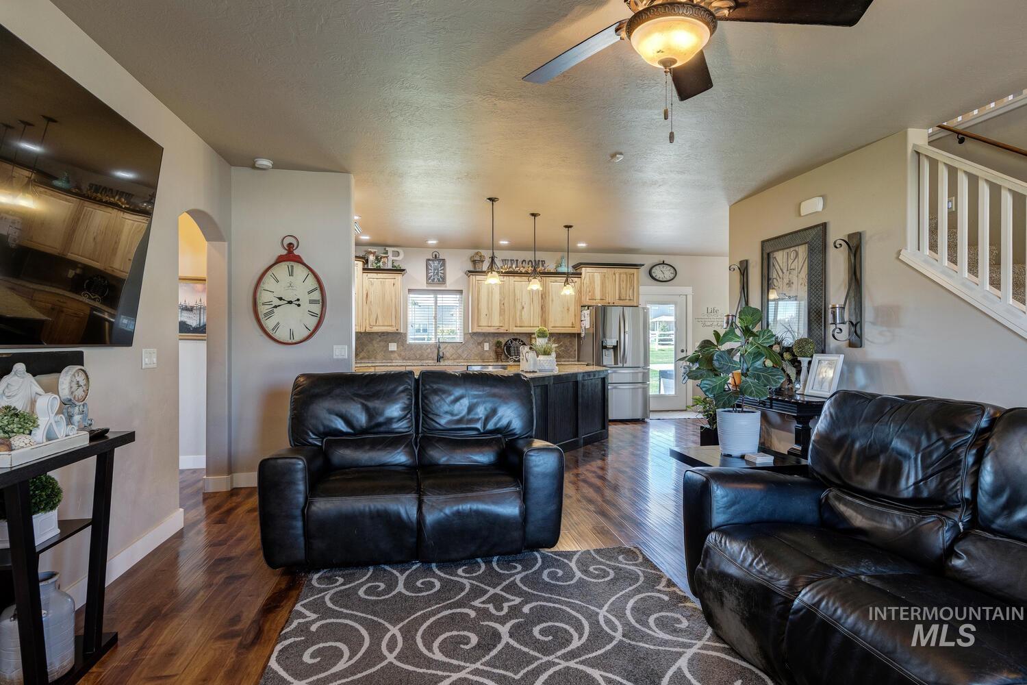 22757 Rosicky Way Caldwell, ID 83607 - Photo 11 of 50 Living room with dark wood-type flooring, arched walkways, ceiling fan, and a textured ceiling