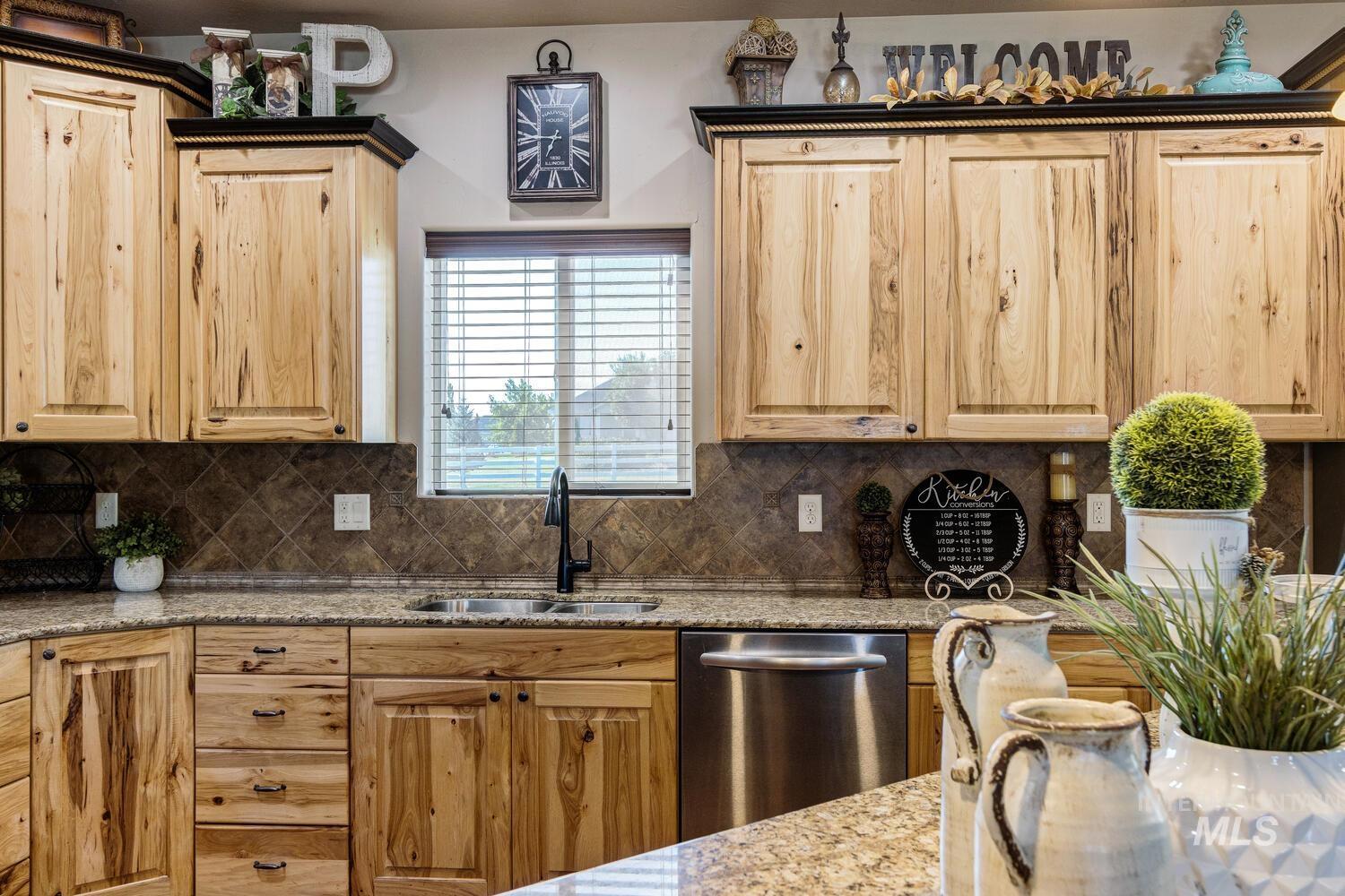 22757 Rosicky Way Caldwell, ID 83607 - Photo 15 of 50 Kitchen with light stone counters, stainless steel dishwasher, tasteful backsplash, and light brown cabinetry