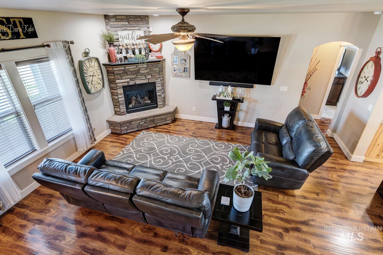 22757 Rosicky Way Caldwell, ID 83607 - Photo 26 of 50 Living room with dark wood-style flooring, ceiling fan, arched walkways, and a stone fireplace
