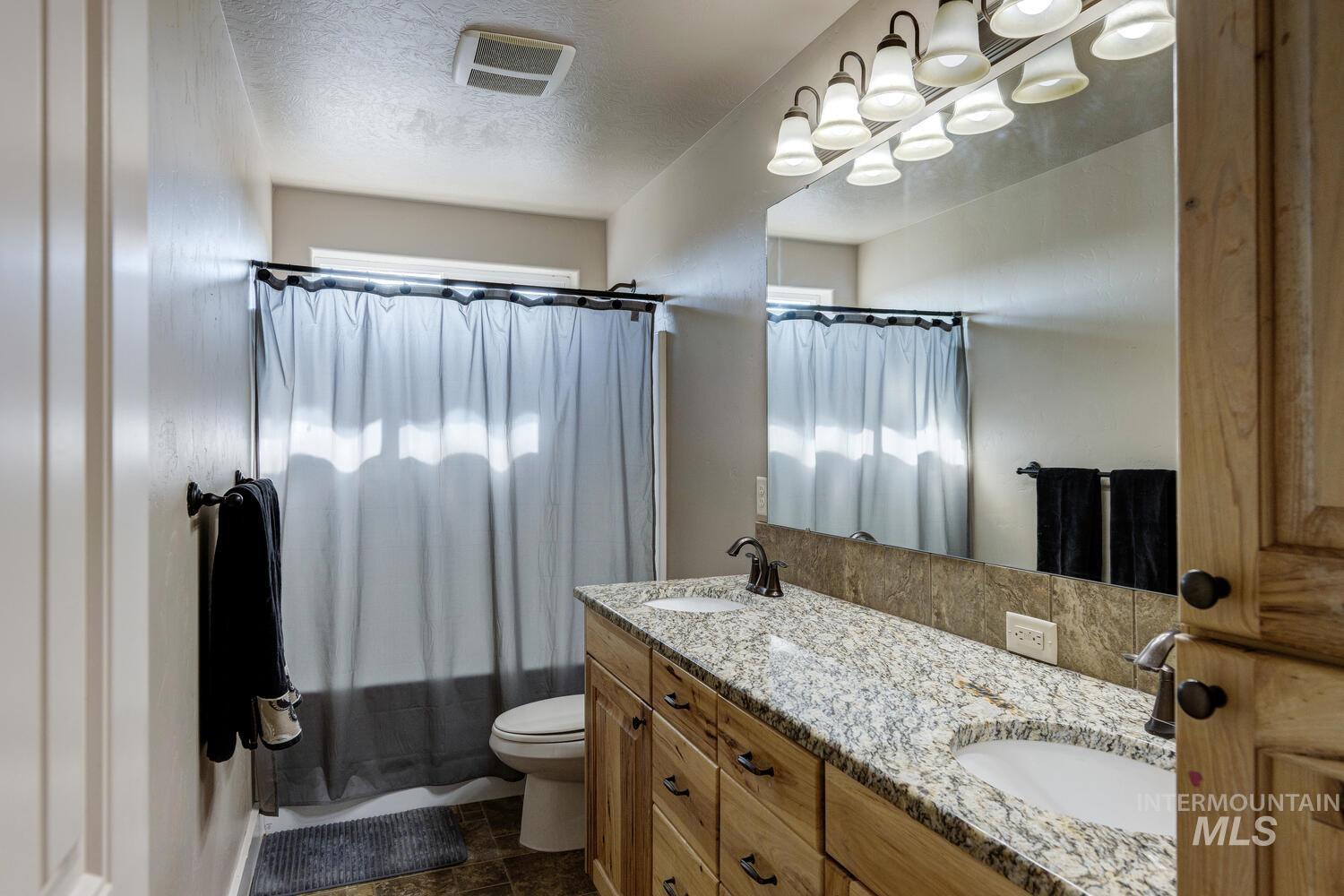 22757 Rosicky Way Caldwell, ID 83607 - Photo 32 of 50 Bathroom featuring double vanity, shower / bath combination with curtain, and a textured ceiling